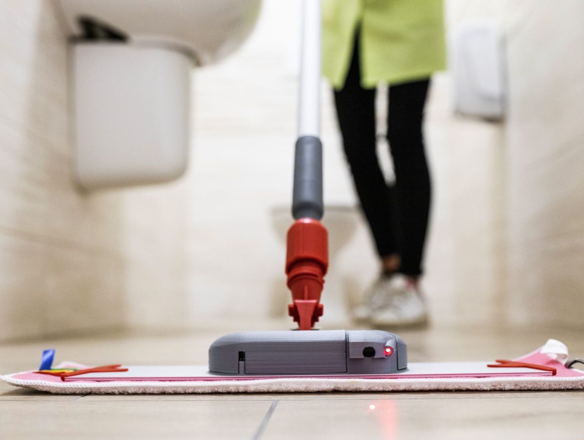 Operatrice al lavoro con il mop Hy-genio in un bagno: postura naturale, senza piegarsi